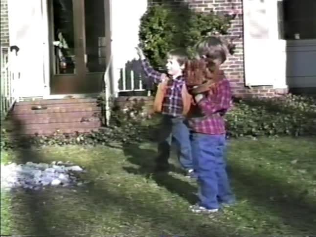Children playing baseball on a residential lawn in front of a house