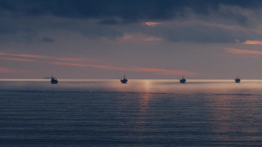 Water in a row of watercraft reflects the sun under a cloudy red tinted sky