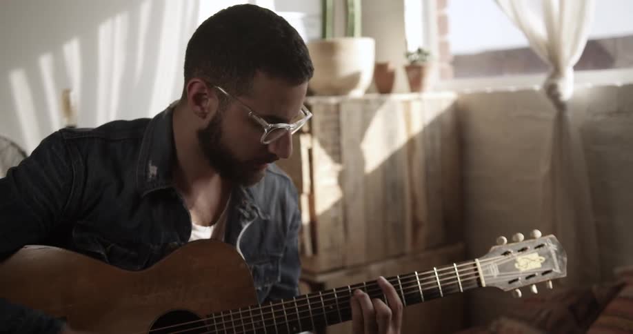 A man plays guitar with a fan behind him