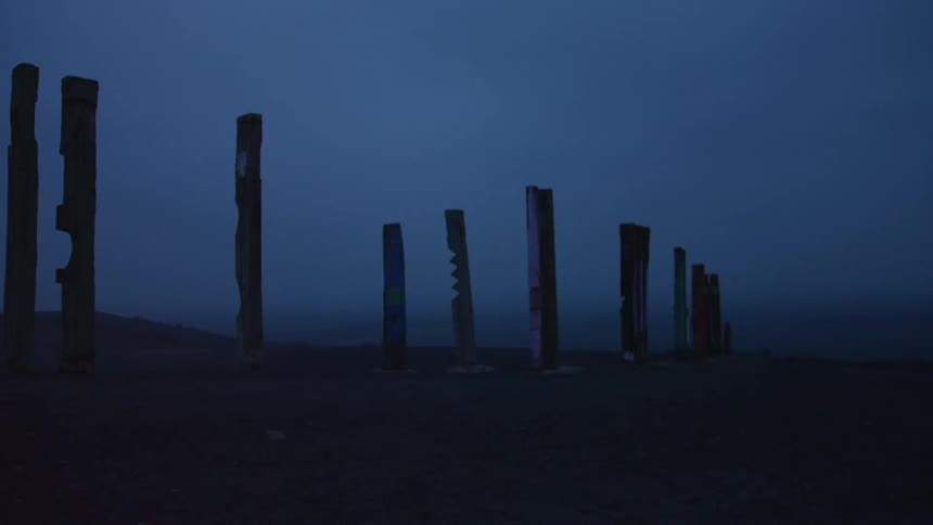Row of posts stands near a slight hill on a foggy evening
