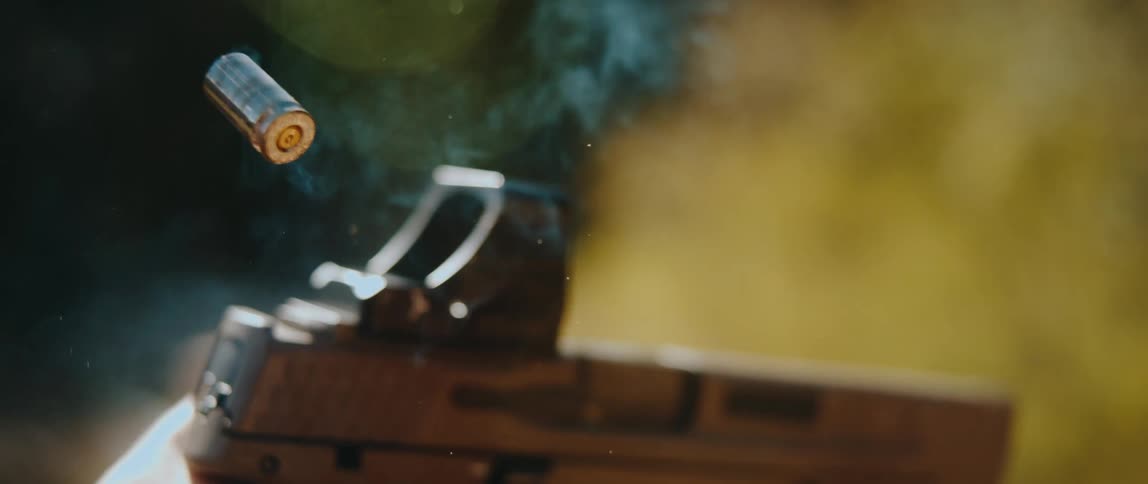 Handgun fires as a bullet shell flies into the air