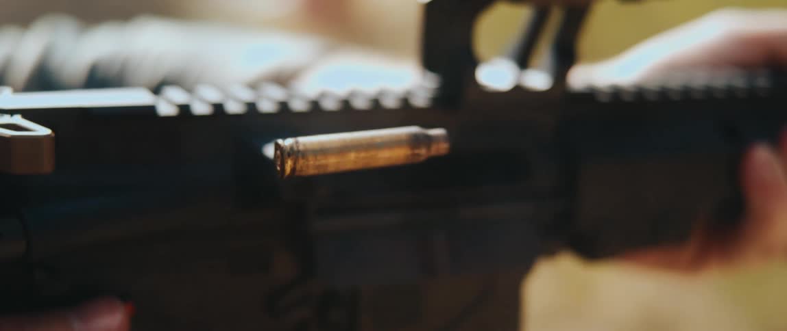 Closeup of a person firing a firearm as a spent bullet casing ejects