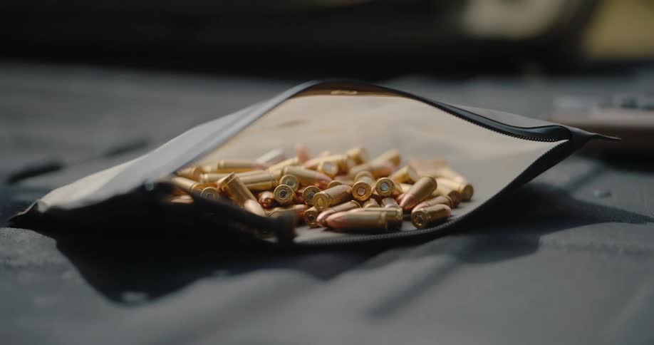 A large number of golden colored bullet are piled inside of a small pouch