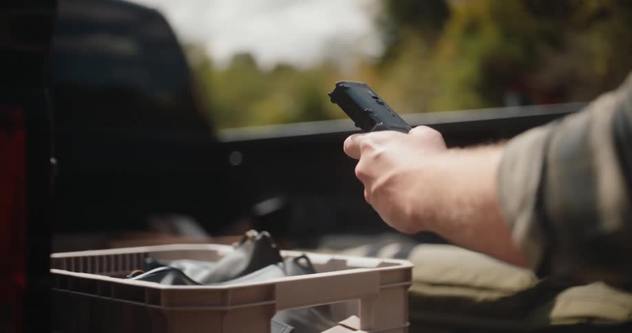 Hand retrieves a gun cartridge from a box