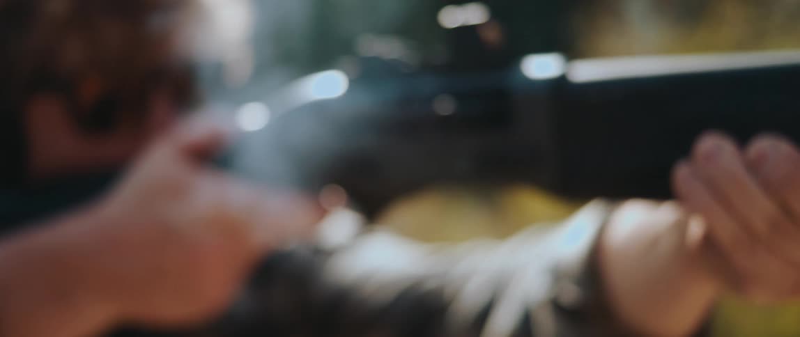 A man fires a shotgun and its shell casing is ejected from the weapon