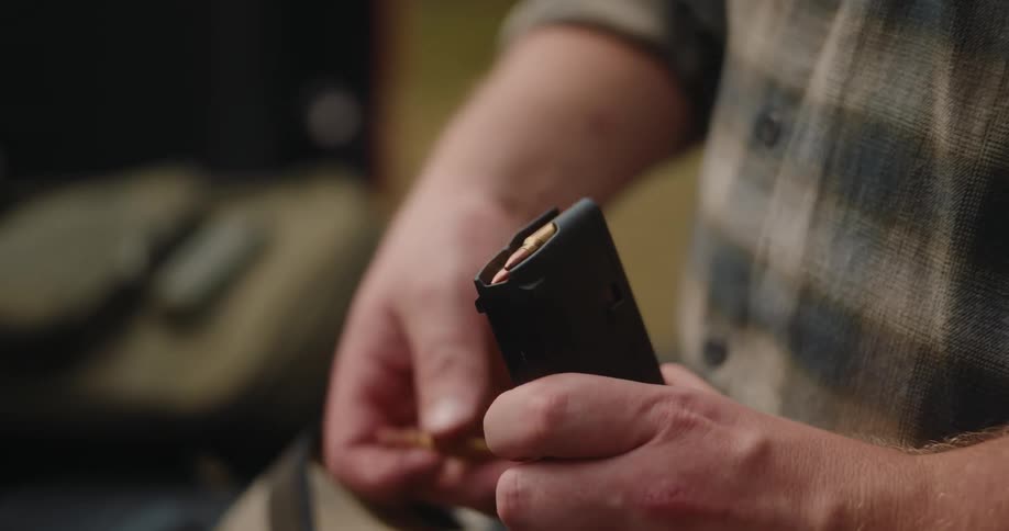 Man is loading bullets into the magazine of his gun
