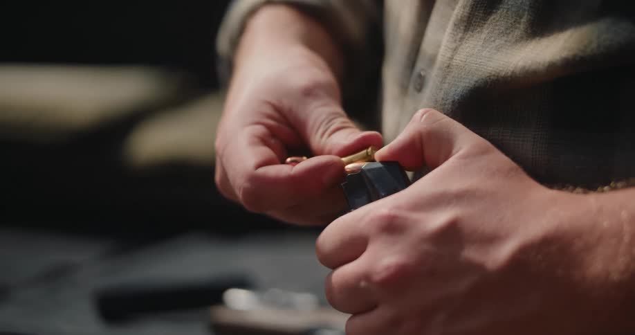 A man loading a gun magazine with bullets