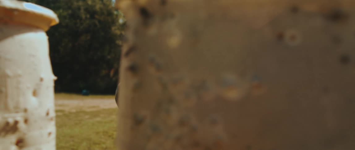 Man stands behind barrels holding a pistol with both hands