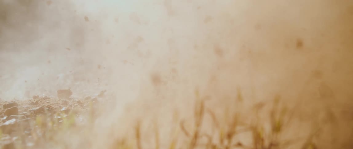 Explosion of dirt and debris occurs near the ground with particles suspended in the air