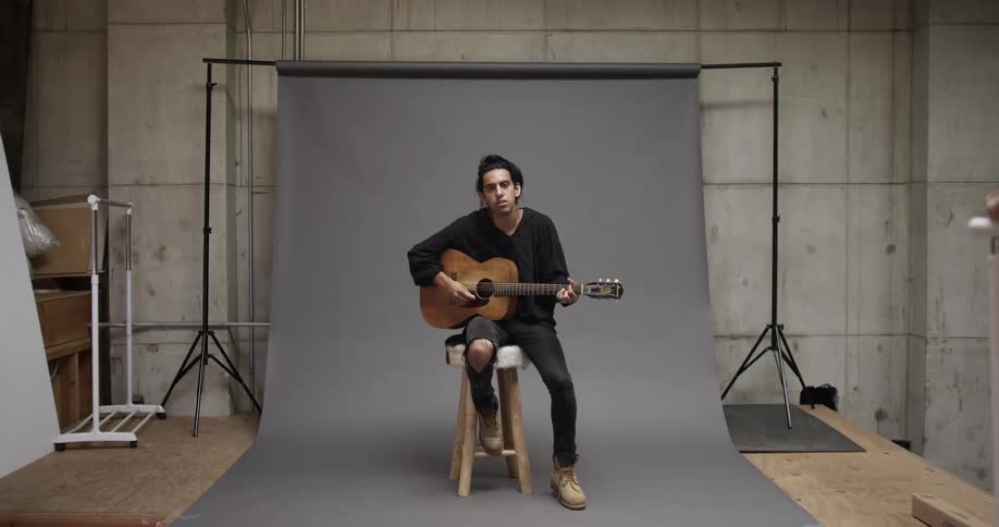 A man plays a guitar in a studio
