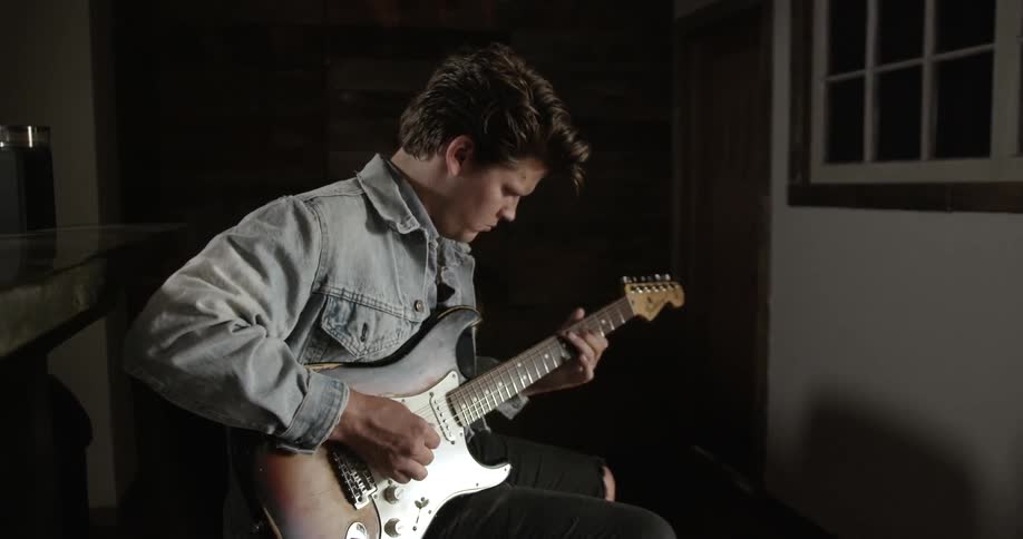 Man playing a guitar in a dark room