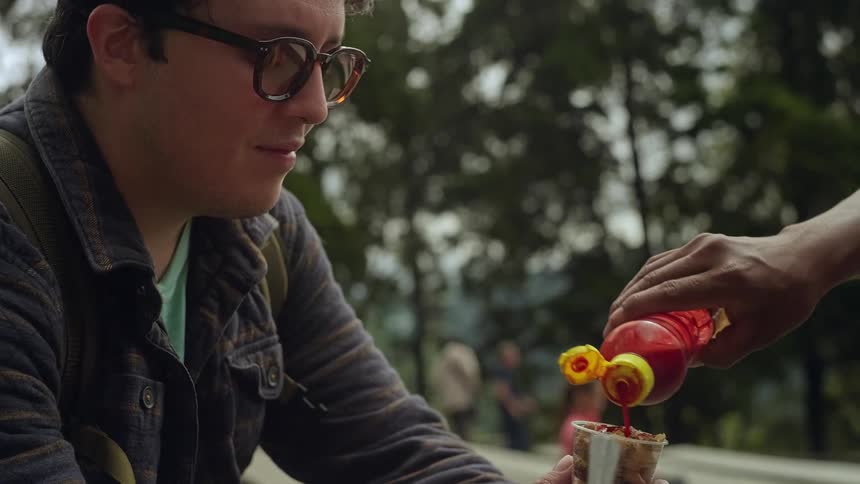 A man holding some food with sauce being poured on it