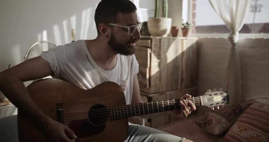 The man plays guitar while he sings