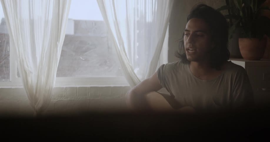 A man plays guitar near a window