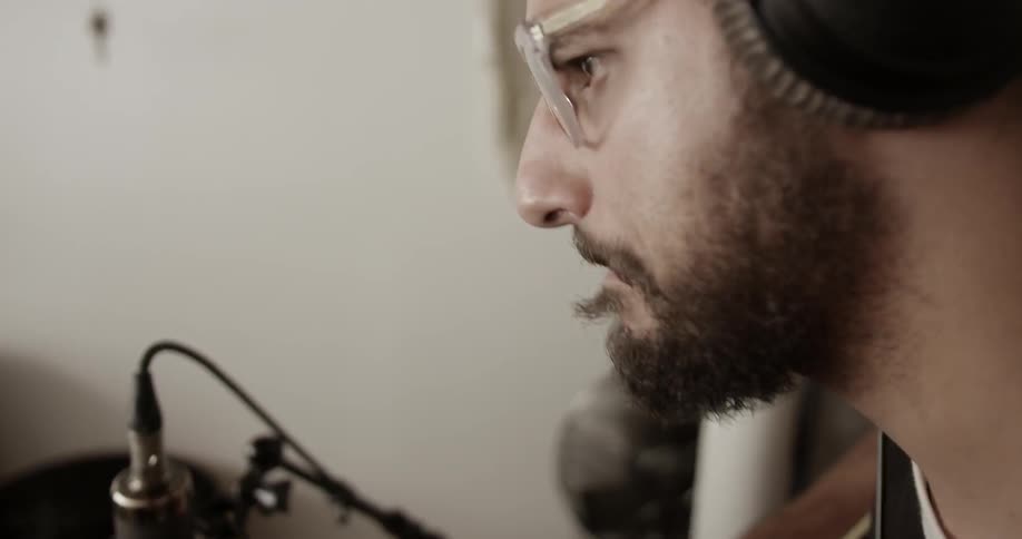 A man is playing guitar into a microphone