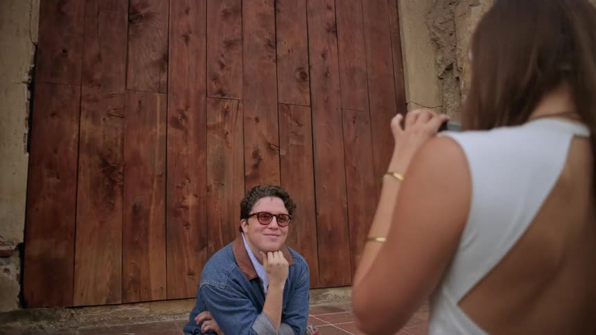 A woman taking a photo of a man in front of a wooden door