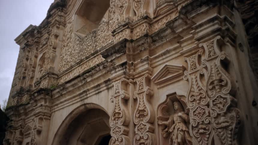 The stone monument has many statues in front