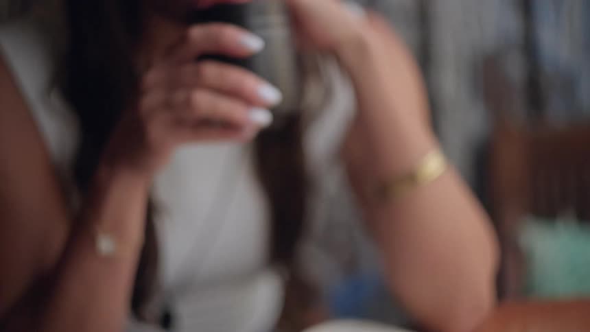 A woman sitting in a room reading and drinking coffee