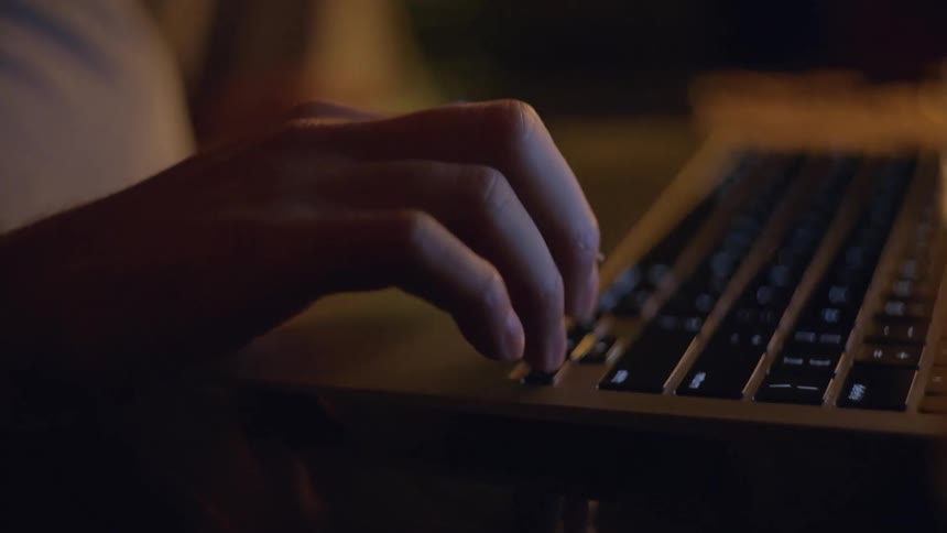 Hand over the keyboard of a laptop computer pushing a button