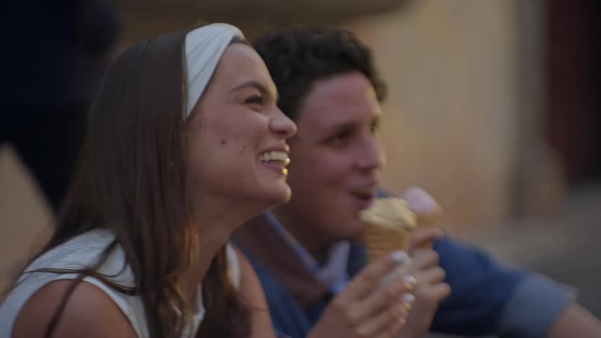 A man and woman eating ice cream cones outdoors