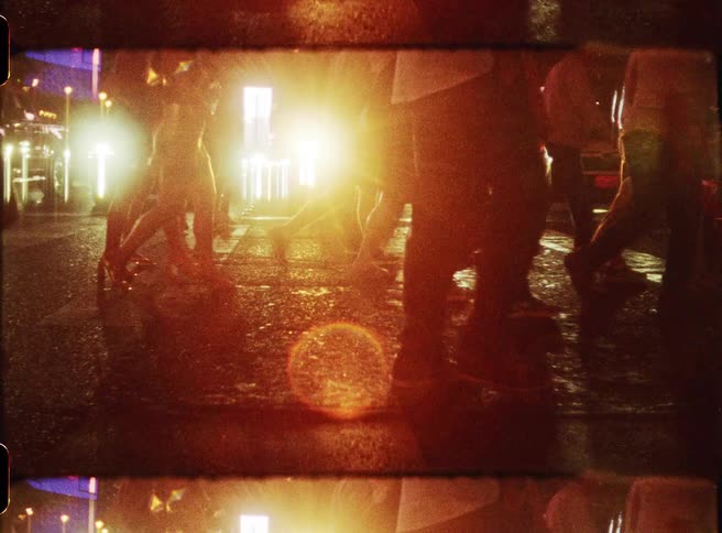 Headlights from the waiting cars shine onto the pedestrians using the crosswalk at night