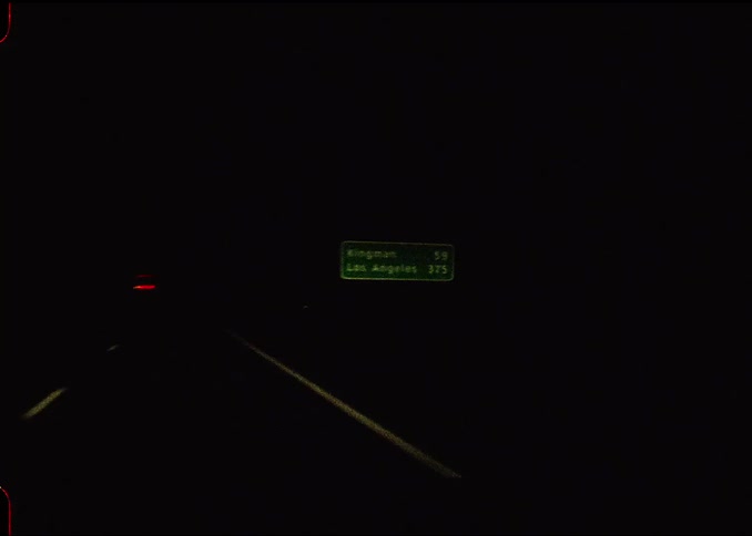 A dark highway stretches ahead at night with glowing road signs and distant car lights