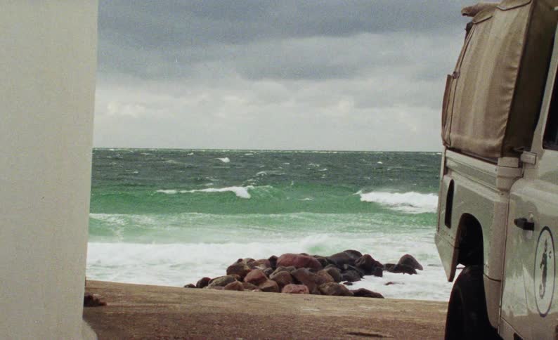 Pickup truck parked in a beach setting with ocean waves in the background
