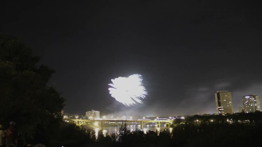 The city ahead is brightly lit as fireworks go off over the bridge