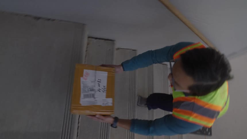 Delivery person leaving a box on the stairs of a residence
