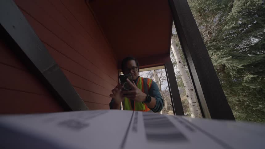Delivery man leaves a package on the porch and takes a picture with his phone as he walks away