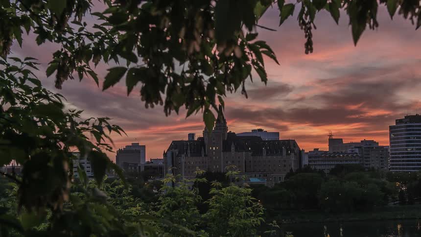 The sun is setting over the large buildings ahead