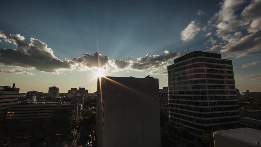 Time lapse of clouds moving over a large city as the sun sets