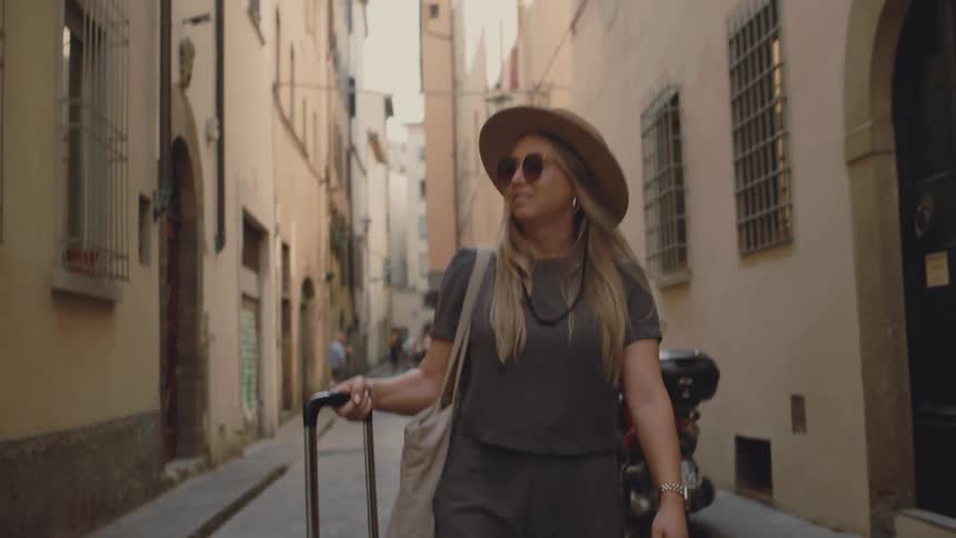 The woman looks up in the city while walking and smiling