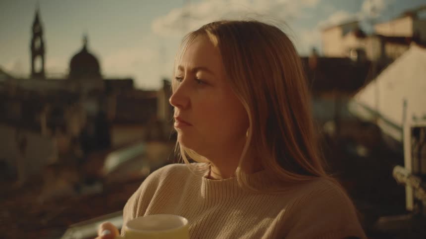 The woman is drinking coffee outside