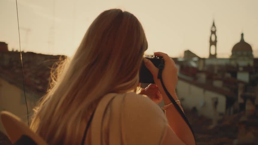 Blonde woman is taking photos of an urban area in the late afternoon