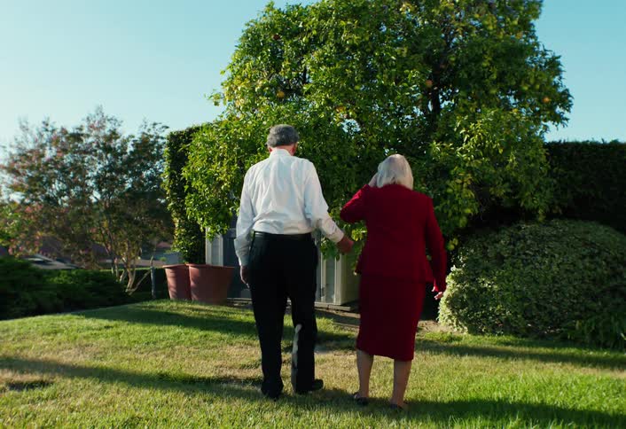 Elderly couple walking together in their backyard