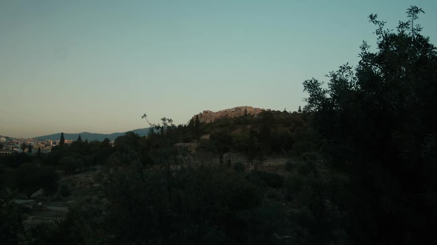 Trees on the mountains and a river valley with city buildings in the distance