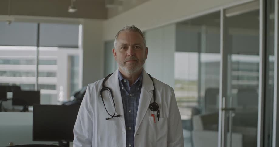 Portrait of older male physician stands in an office during the daytime