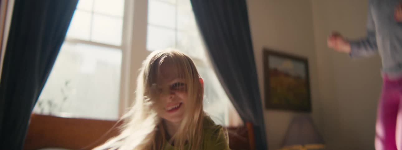 Two children jumping on a bed and playing