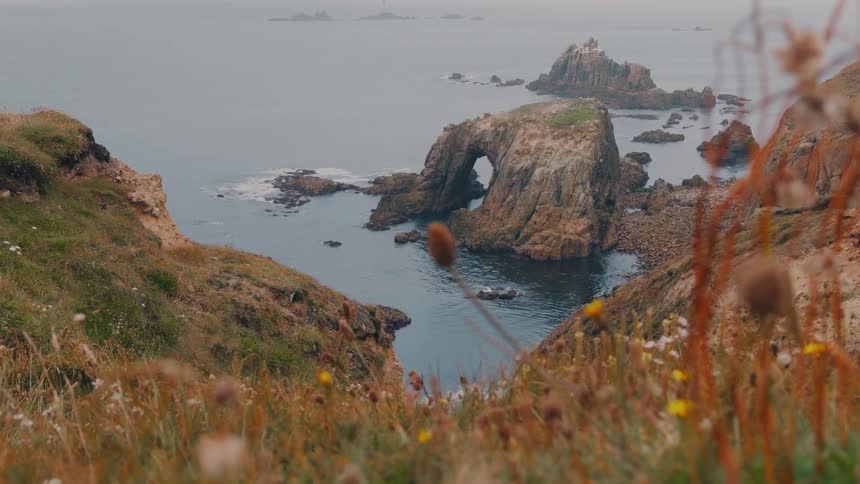 Scenic rugged coastal cliffs frame a natural rock arch above calm ocean waters
