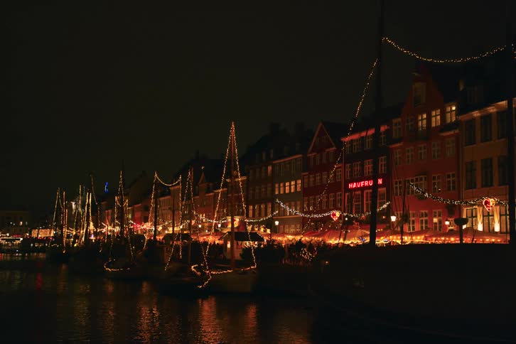 Strings of lights decorate the waterfront including the boats at night