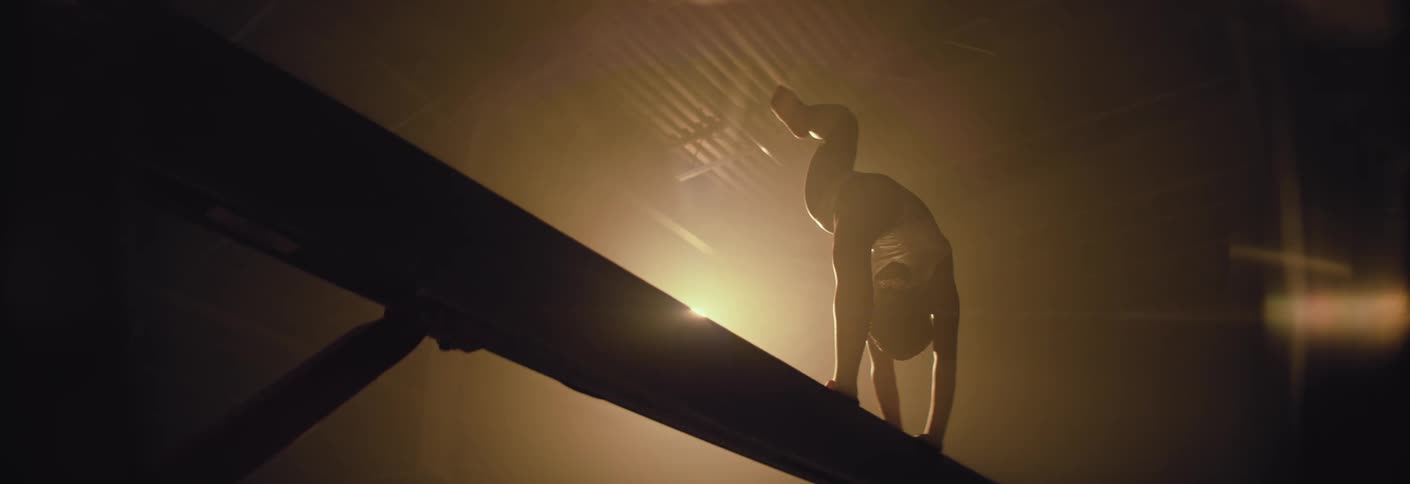 The woman is doing gymnastics on the balancing beam