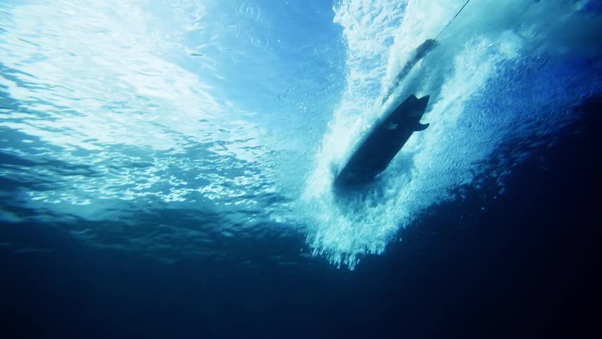 The surfer is paddling on his surfboard in the ocean