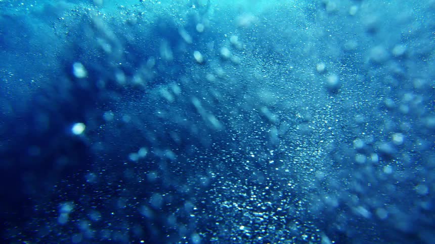 Suspended particles illuminated in deep blue tones in an underwater environment