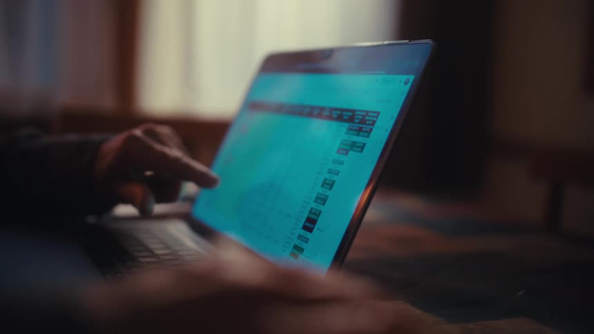 Elderly man reviewing financial data on a laptop in a quiet home workspace