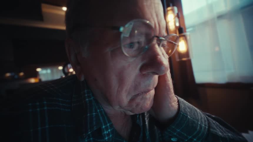 Elderly man taking off his glasses