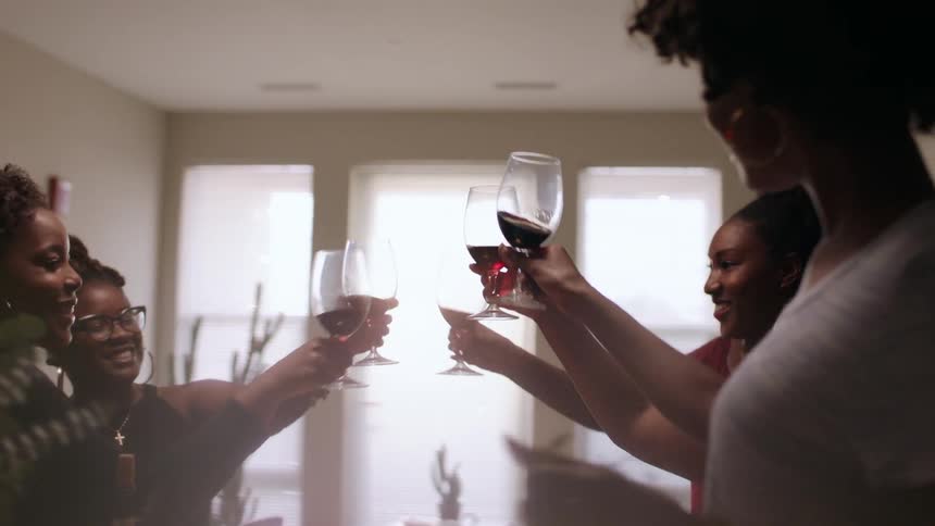 A group of women hold up glasses of wine in a toast