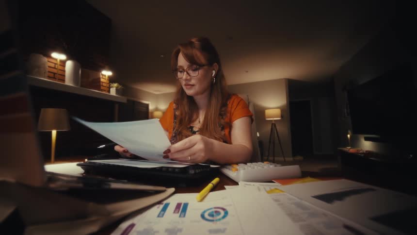 A woman showing paper documents to a laptop