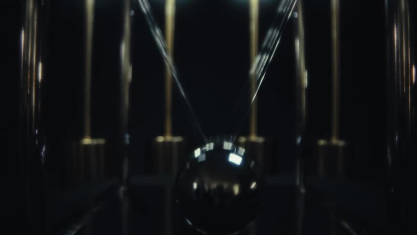 A symmetrical shot of a newtons cradle swinging under glowing lights on a dark background