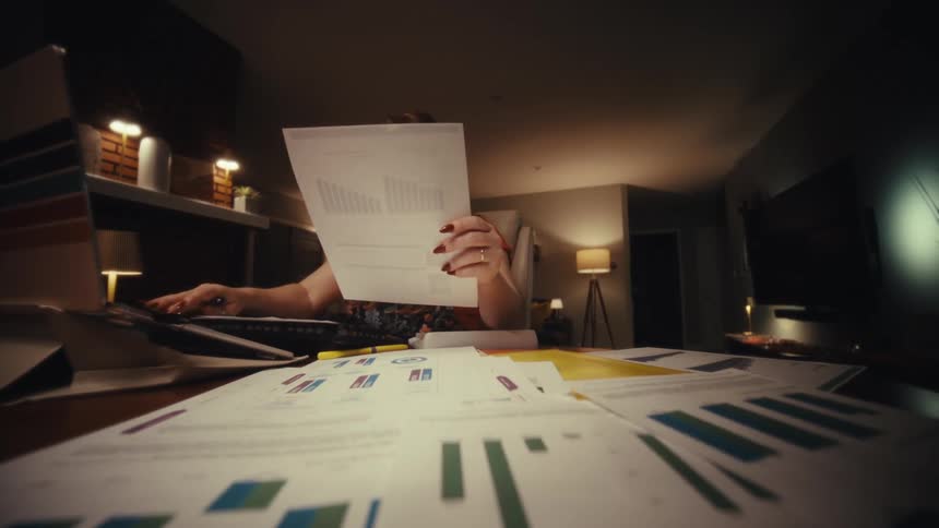 Woman working with documents and a laptop at an office desk